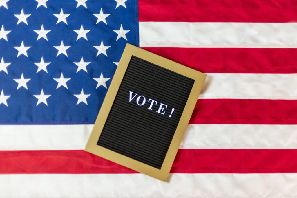 Letter board sign with the word VOTE on American flag background
